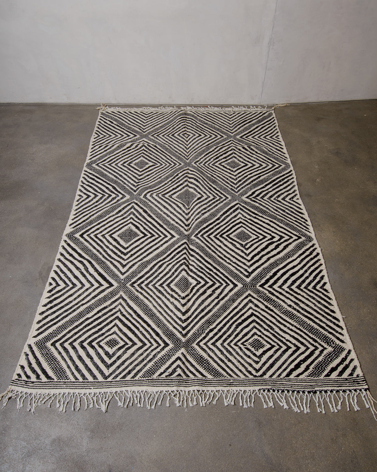 Black and white geometric patterned rug on a concrete floor